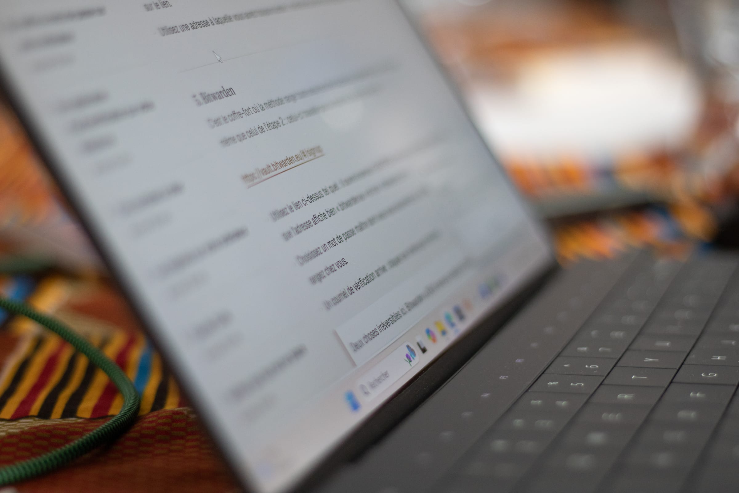 L’écran d’un ordinateur portable ouvert sur le guide de préparation, à l’étape « Bitwarden », posé sur une nappe kente pendant la première édition.